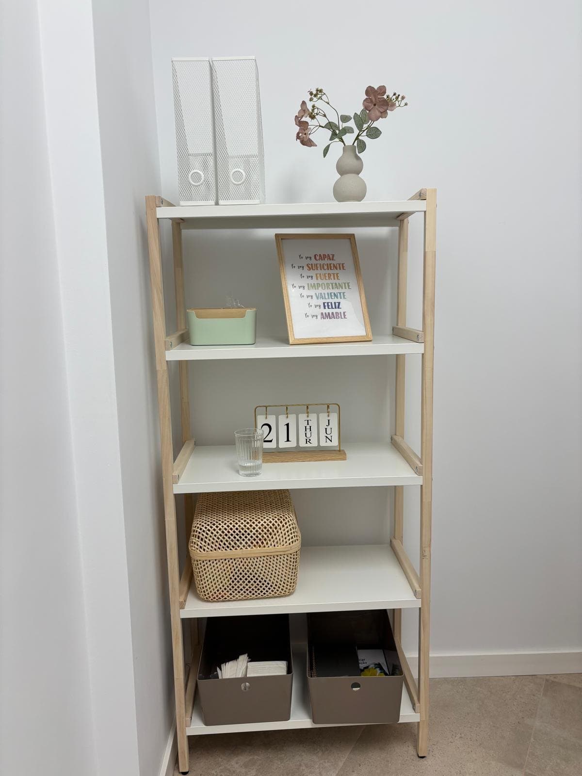 Estantería con flores, cestas y una lámina de afirmaciones