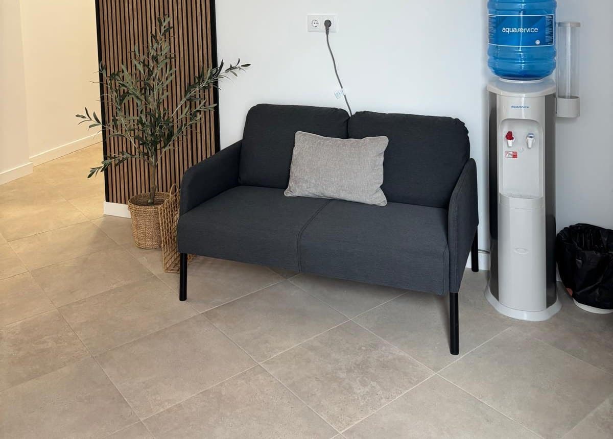 Sala de espera con sofá, planta y pared de listones de madera